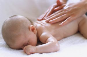 Baby massage. Hands massaging the back of a 2-month-old baby boy. Massage is used to promote relaxation, relieve muscle spasms, and to prevent oedema (build-up of fluid). It is thought to also relieve colic (trapped wind) in babies. It also indulges a baby's need for attention. --- Image by © Ian Hooton/Science Photo Library/Corbis